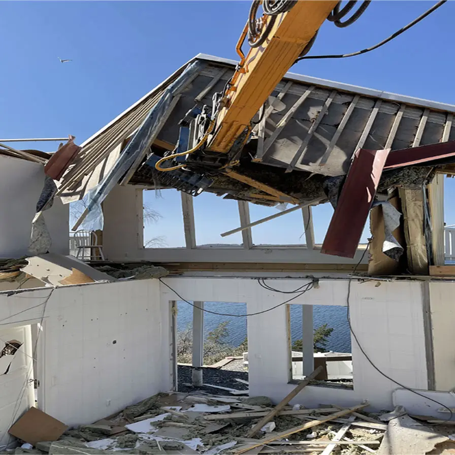 Rivning av hus Dalarö med havsutsikt. Rivningsgrip på en grävmaskin
